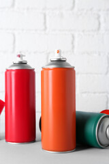 Wall Mural - Cans of spray paint on wooden table near white brick wall