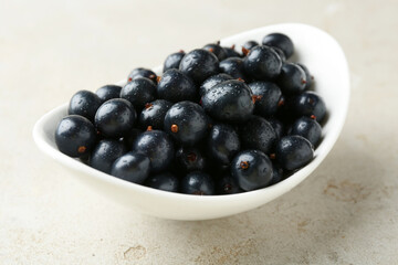 Wall Mural - Ripe black currants in bowl on light table, closeup