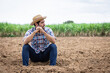 © kamonrat - Contemplative Farmer Sitting on Barren Land, Reflecting on the Challenges of Agriculture, Drought, and the Unpredictability of Nature in a Rural Farm Setting