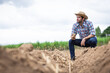 © kamonrat - Farmer Inspecting Soil Quality on Barren Farmland, Assessing Agricultural Conditions and Preparing for Future Cultivation in Rural Environment Under a Cloudy Sky