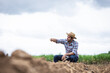 © kamonrat - Farmer Inspecting Soil Quality on Barren Farmland, Assessing Agricultural Conditions and Preparing for Future Cultivation in Rural Environment Under a Cloudy Sky