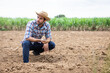 © kamonrat - Farmer Inspecting Soil Quality on Barren Farmland, Assessing Agricultural Conditions and Preparing for Future Cultivation in Rural Environment Under a Cloudy Sky