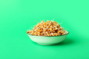 Wall Mural - Bowl with sprouted wheat on green background