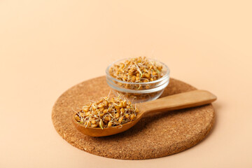 Wall Mural - Wooden board with spoon and bowl of sprouted wheat on beige background