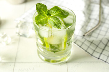 Wall Mural - Glass of tasty mojito on light tile background