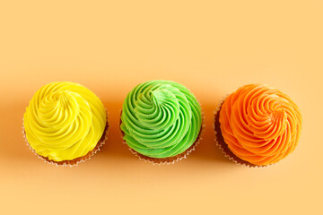 Wall Mural - Tasty colorful cupcakes on orange background