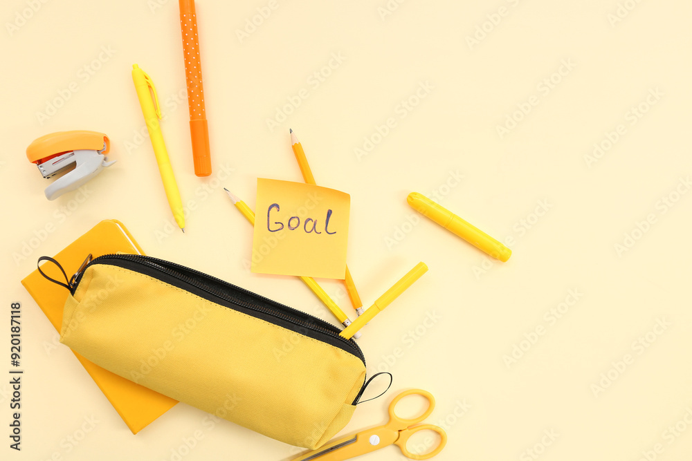 Sticky note with word GOAL and school stationery on beige background