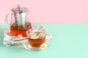 Wall Mural - Teapot with cup of natural chamomile tea and flowers on turquoise table near pink wall