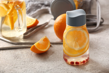 Wall Mural - Sports bottle of infused water with orange slices on grey table