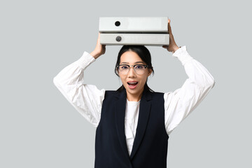 Sticker - Portrait of young Asian businesswoman with office folders on grey background