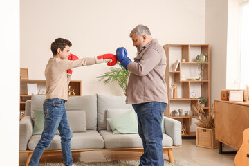 Wall Mural - Happy grandfather and his cute grandson during boxing training at home