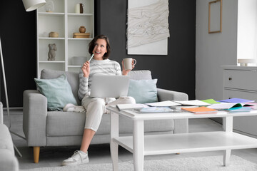 Canvas Print - Thoughtful female student with cup and laptop studying on sofa at home