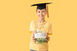 © Pixel-Shot - Teenage girl in mortar board holding money jar with text COLLEGE on yellow background. Tuition fees concept