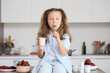 © Pixel-Shot - Cute little girl with yogurt pack and spoon sitting on table in kitchen