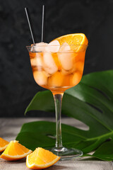 Wall Mural - Glass of Aperol spritz cocktail and palm leaf on grey tile table