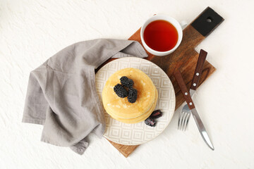 Wall Mural - Plate of sweet pancakes with fresh blackberries, honey and cup of tea on white background