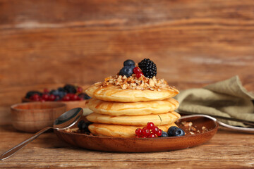 Wall Mural - Plate of sweet pancakes with fresh berries and nuts on wooden background