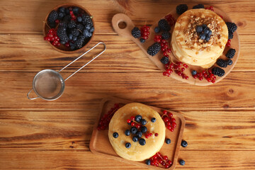 Canvas Print - Boards of sweet pancakes with different fresh berries and nuts on wooden background