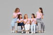© Pixel-Shot - Beautiful women with pink ribbons sitting on sofa against light background. Breast cancer awareness concept