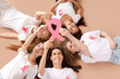 © Pixel-Shot - Beautiful women with pink ribbons lying on beige background, top view. Breast cancer awareness concept