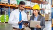 © N7 - Indian manager and logistics employee reviewing shipping paperwork and product orders in a warehouse setting.