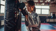 © Mahemud - A girl in a kimono practicing karate with a punching bag in the gym.
