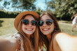 © lashkhidzetim - Two women wearing sunglasses and hats are smiling for the camera. Scene is cheerful and lighthearted