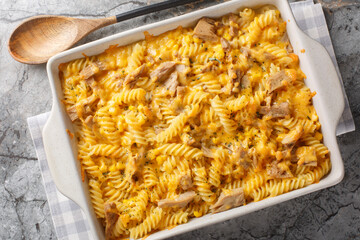 Tuna mornay is a classic Australian cheesy tuna pasta bake closeup on the baking dish on the table. Horizontal top view from above