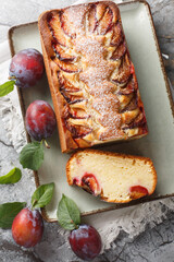 Wall Mural - Tasty yogurt plum cake made with yogurt and olive oil is light, moist and delicious for brunch and dessert closeup on the plate on the table. Vertical top view from above