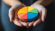 © supee - Close-up of hands holding a pie chart showing 2024 financial distribution