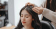 © Marina Varnava - Young Chinese woman experiencing hair thinning in a beauty salon while sitting in an armchair with a professional examining her scalp
