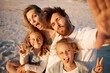 © Lumeez23/peopleimages.com - Parents, kids and selfie at beach, funny face or smile with care, love or tongue out for memory in summer. Father, mother and daughter children with peace sign, family or portrait on holiday in Spain