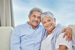 © peopleimages.com - Hug, portrait and smile with senior couple on sofa of home living room together for bonding. Happy, marriage or relax with elderly man and woman in apartment for relationship, retirement or romance