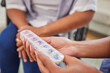 © Lumeez23/peopleimages.com - Woman, nurse and hands with pills for patient, prescription or weekly supplement at home. Closeup of caregiver talking to client with box or container for pharmaceutical medication or dosage at house
