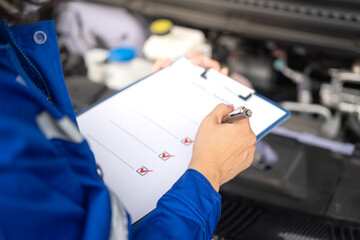 Wall Mural - action of a mechanic worker in blue uniform is using a pen to checking on safety checklist form to v