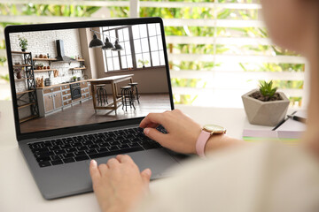 Wall Mural - Woman looking for house on real estate market website at table, closeup