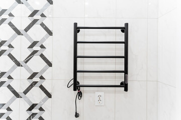 A sleek black towel rack is elegantly hanging on a pristine white tiled wall in the bathroom, adding a touch of modernity to the overall design and functionality of the space