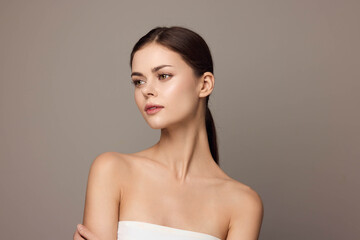 Photo of beautiful young woman in a white dress posing with hands on her hips and looking at the camera, isolated on a gray background