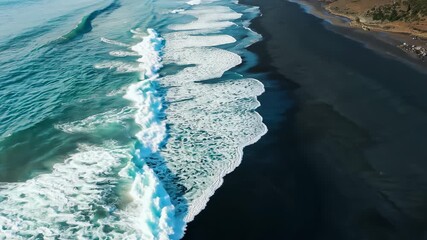 Wall Mural - Aerial view of ocean waves crashing on the beach during sunset at a coastal location