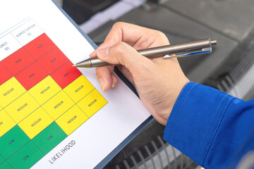 Wall Mural - an engineer is using a pen to checking on the safety risk assessment with color matrix form to evalu