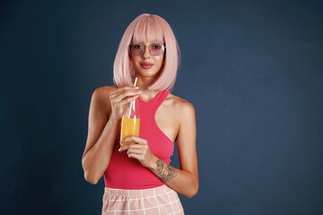 Wall Mural - Pink hair, with orange juice. Beautiful young woman is against background