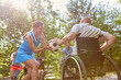 © Robert Kneschke - Inclusive outdoor recreation, person in wheelchair enjoying football with friends in a park