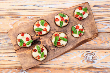 Poster - Italian mini pizza . Aubergine (eggplant ) with mozzarella cheese and basil . On rustic background