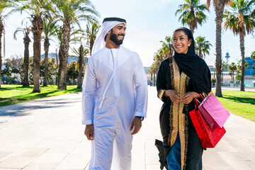 Traditional arab couple wearing emirati clothing dating outdoors - Middle-eastern married woman with abaya and man with kandura meeting and having fun in the city