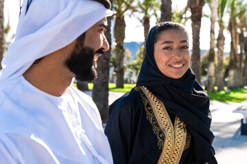 Traditional arab couple wearing emirati clothing dating outdoors - Middle-eastern married woman with abaya and man with kandura meeting and having fun in the city