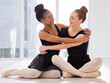 © Nina2024/peopleimages.com - Ballet, hug and smile with woman, friends on floor with dance together for bonding and rehearsal. Art, creative and love with happy ballerina people, embracing and studio for theatre recital