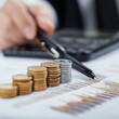© N. W. - business man stacking coins on a table to show savings and financial education
