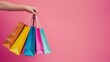 © Joyce - Hand holding shopping bags over plain background