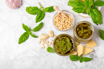 Pesto. Italian basil pesto sauce on a textured wooden background. Ingredient for pesto sauce: fresh basil, pine nuts, Parmesan cheese and olive oil. Space for text.Copy space.