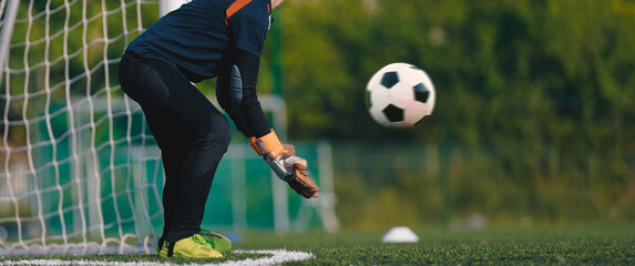 Wall Mural - Soccer goalkeeper in gloves with a soccer ball in motion. Football training for young goalies